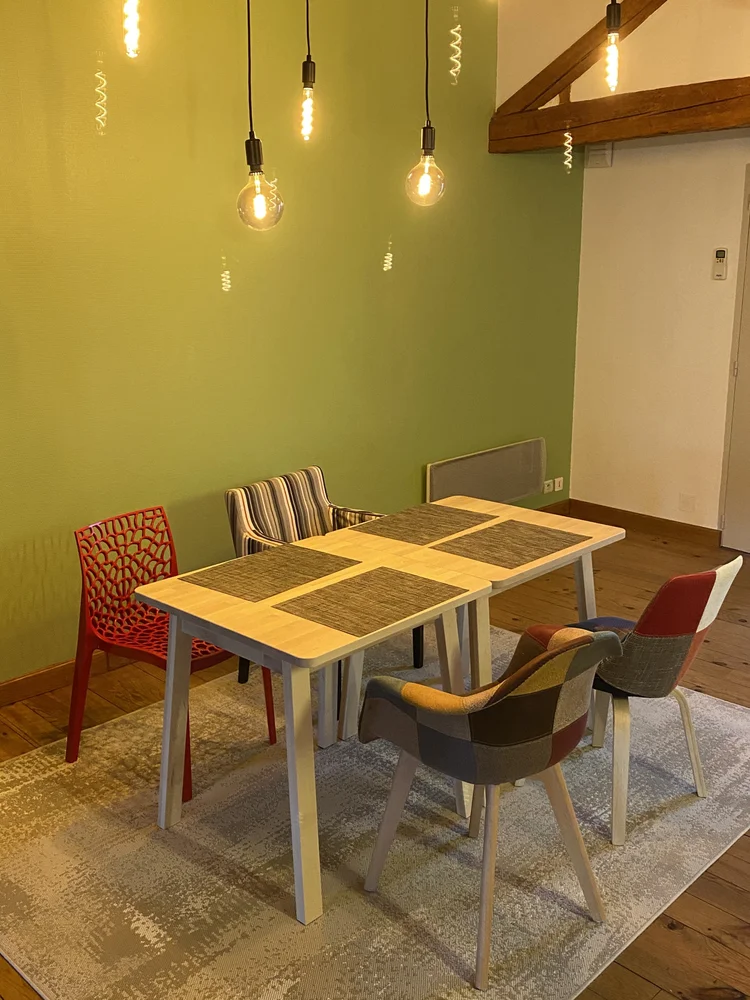 Salle à manger aux murs verts et suspensions à ampoules