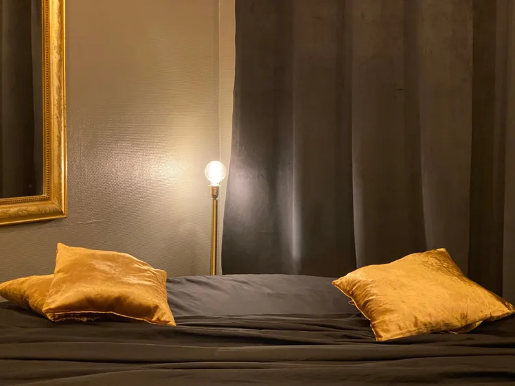 Lit de la love room éclairé par des lampes tamisées